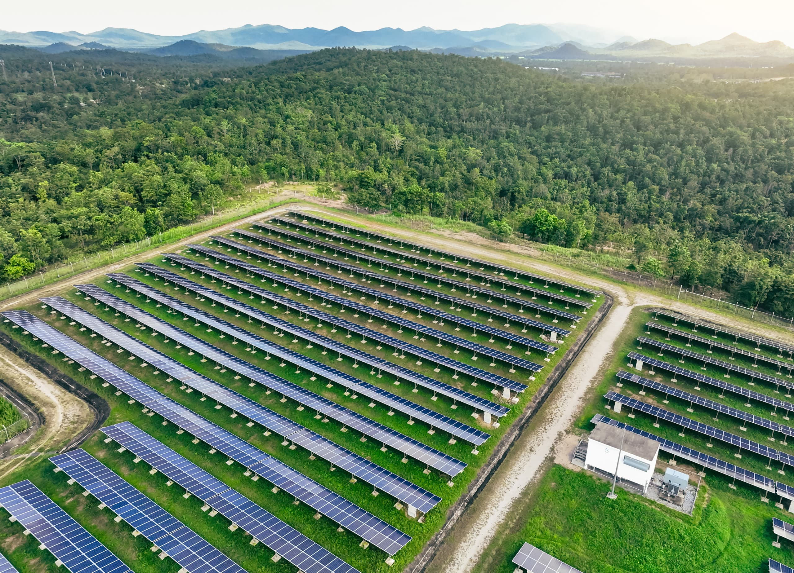 A solar energy field with solar panels gleaming under the sunlight, surrounded by a natural landscape.