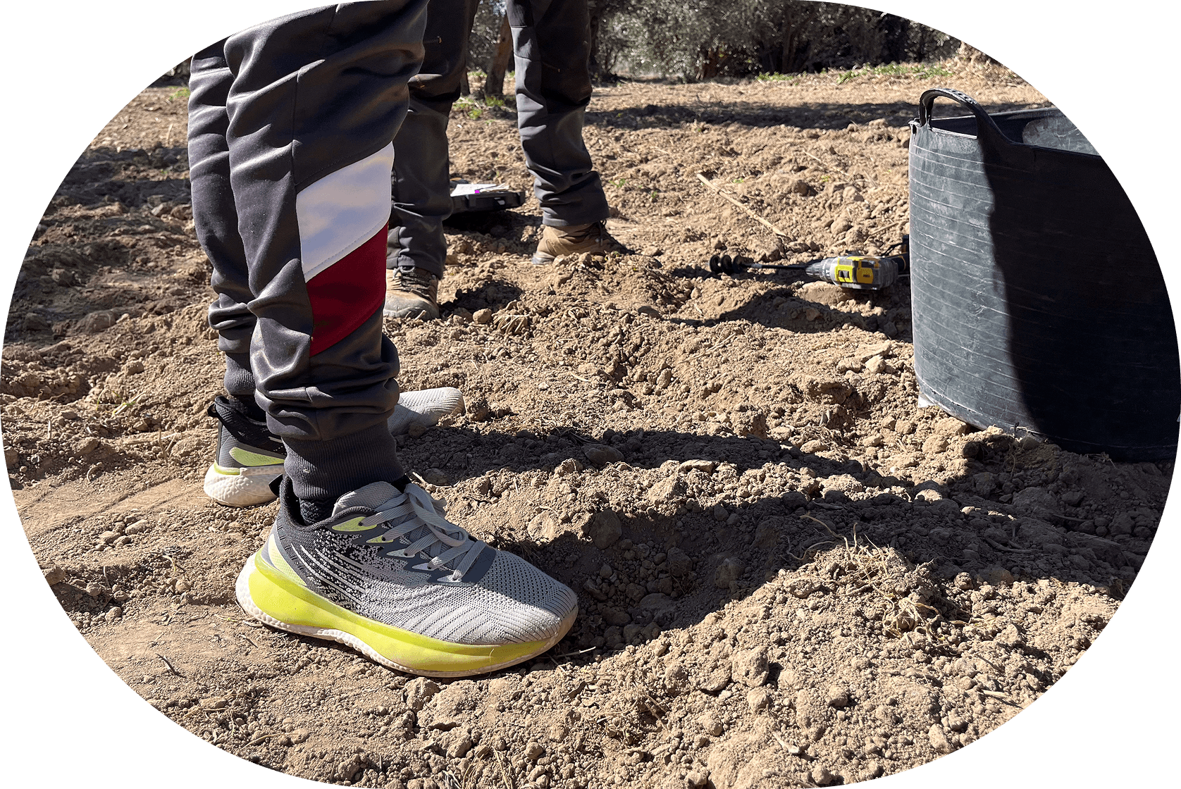 A person stands on dirt holding a bucket, ready to engage in an outdoor activity or task.